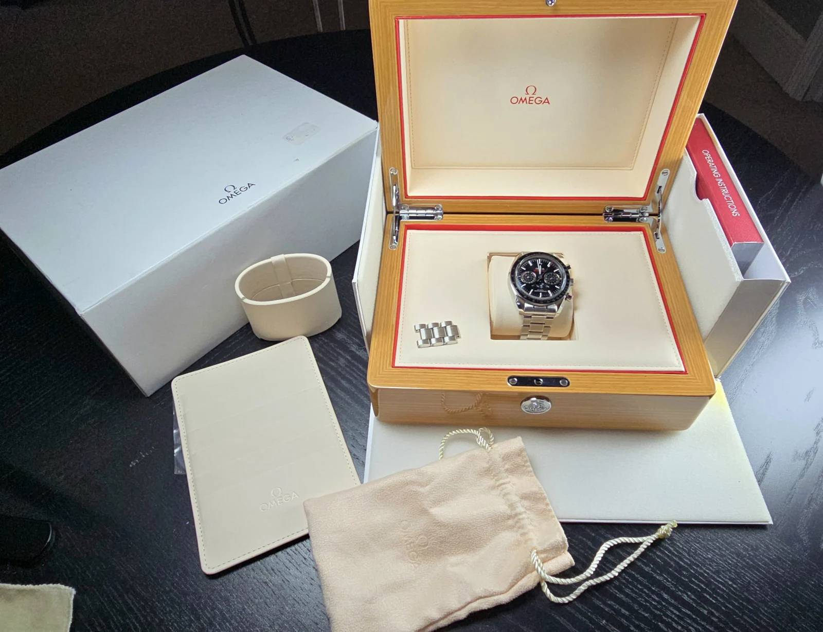 Omega Speedmaster Moonphase 304.30.44.52.01.001 in its open wooden presentation box with spare bracelet links and accessories