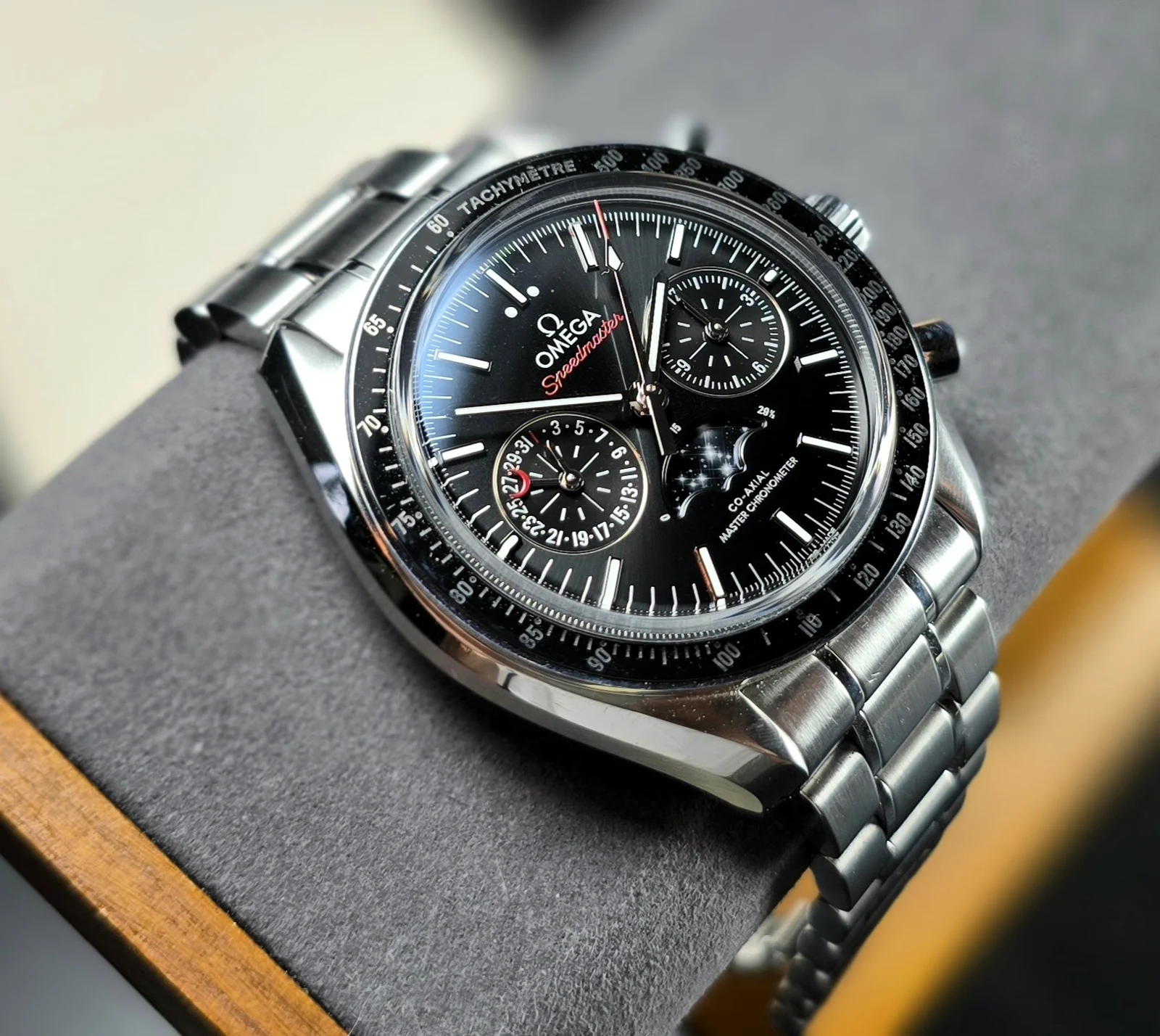 Oblique view of Omega Speedmaster Moonphase 304.30.44.52.01.001 with black dial, ceramic tachymeter bezel and steel bracelet